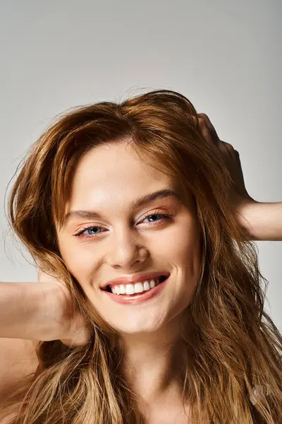 Retrato de belleza de mujer sonriente con maquillaje natural, mirando a la cámara tocando su cabello - foto de stock