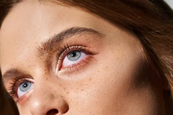 Nahaufnahme Schönheit Porträt der Frau blaue Augen mit Pfirsich Make-up und Sommersprossen auf grauem Hintergrund — Stockfoto