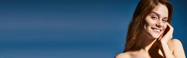 Plan beauté de femme souriante, maquillage pêche et taches de rousseur touchant la joue sur fond bleu, bannière — Photo de stock