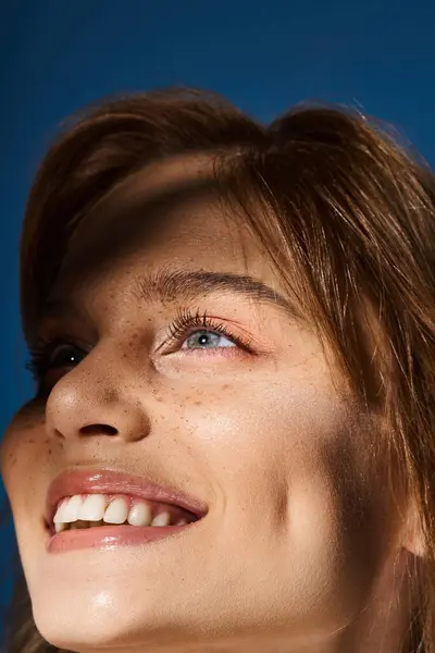 Primo piano ritratto di bellezza sorridente donna dagli occhi blu con lentiggini su sfondo blu scuro — Foto stock