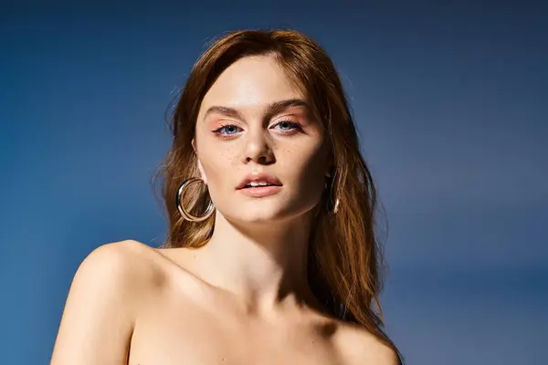Schönheitsporträt einer hübschen jungen Frau mit natürlichem Make-up, die in die Kamera auf blauem Hintergrund blickt — Stock Photo