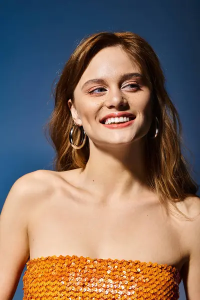 Mujer sonriente confiada mirando hacia otro lado con maquillaje natural de melocotón desnudo, sobre fondo azul - foto de stock