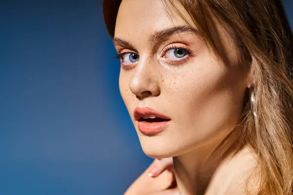 Closeup side view photo of girl with blue eyes, peach nude makeup with freckles on blue background — Stock Photo