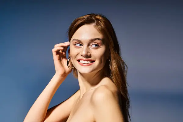 Vista lateral de la foto de belleza de la mujer alegre sonriendo, tocando su cabello sobre fondo azul oscuro - foto de stock