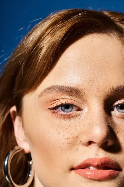 Closeup retrato de beleza do rosto da mulher com olhos azuis, maquiagem pêssego e sardas no fundo azul — Fotografia de Stock