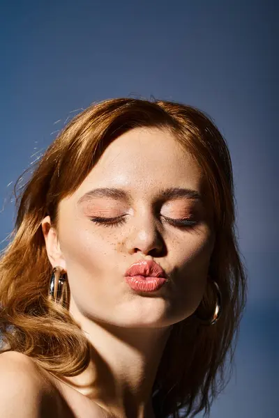 Primo piano di una bella donna attraente che invia baci colpo alla fotocamera, su sfondo blu — Foto stock