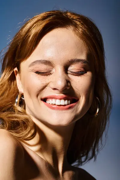 Primo piano colpo di bella donna attraente sorridente con gli occhi chiusi, su sfondo blu — Foto stock