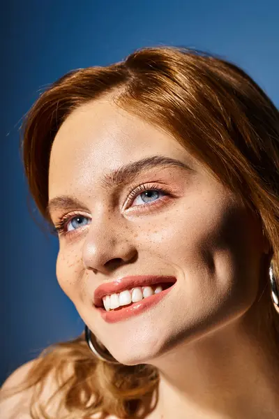 Gros plan beauté de femme souriante aux yeux bleus, maquillage pêche et taches de rousseur sur fond bleu — Photo de stock