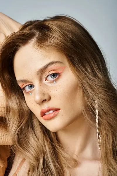 Closeup portrait of attractive woman in beige jacket with tear face jewels, looking at camera — Stock Photo