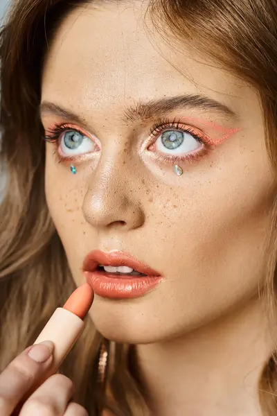 Closeup beauty shot of woman with peach makeup eyeliner, pink lipstick, face jewels and freckles — Stock Photo