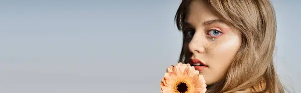 Closeup beauty shot of woman with peach makeup eyeliner, gerbera daisy, face jewels, banner — Stock Photo