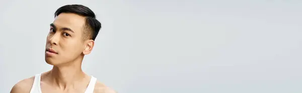 Bello asiatico uomo in canotta bianca posa in grigio studio impostazione, banner — Foto stock