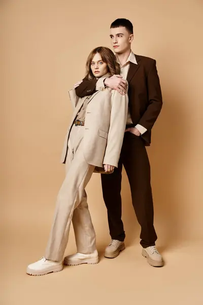 Elegante hombre guapo en traje debonair posando junto a su hermosa novia que mira a la cámara - foto de stock