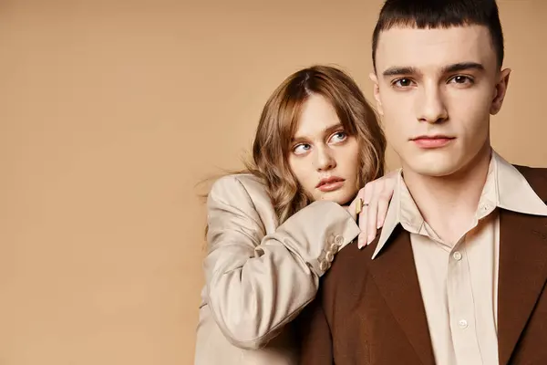 Atractiva mujer elegante en traje elegante posando junto a su novio guapo que mira a la cámara - foto de stock