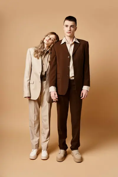 Sofisticado hombre en traje debonair posando junto a su hermosa novia que mira a la cámara - foto de stock