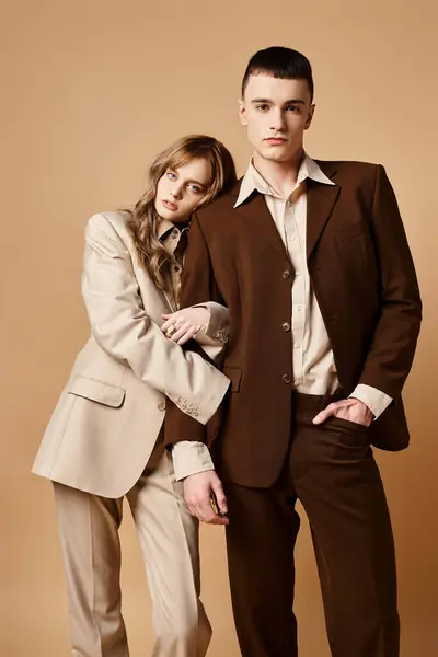 Alluring elegant couple in debonair suits posing together and looking at camera on pastel backdrop — Stock Photo