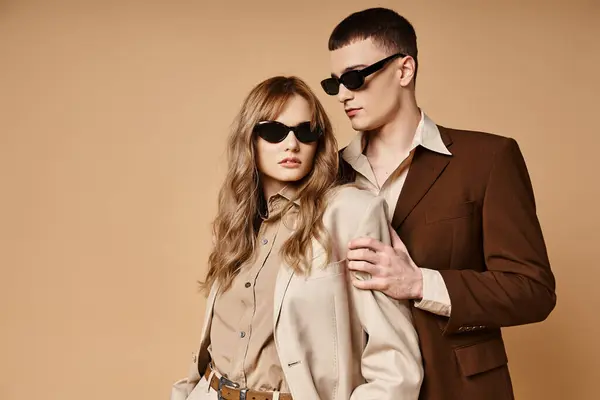 Seducente coppia elegante in abiti stagionali chic con occhiali da sole alla moda in posa su sfondo pastello — Foto stock