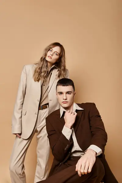 Reizvolles Paar in edlen Anzügen posiert zusammen und blickt vor pastellfarbener Kulisse in die Kamera — Stock Photo