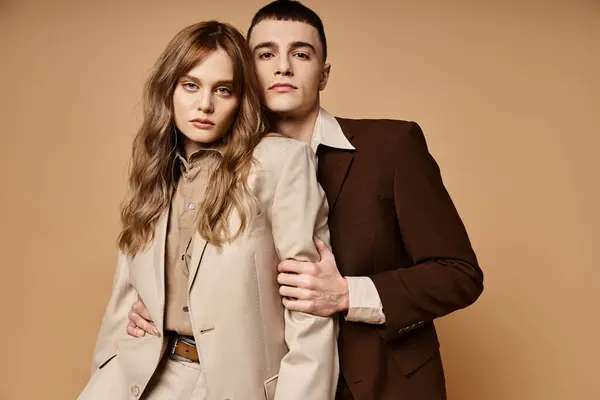Reizvolles Paar in edlen Anzügen posiert zusammen und blickt vor pastellfarbener Kulisse in die Kamera — Stock Photo