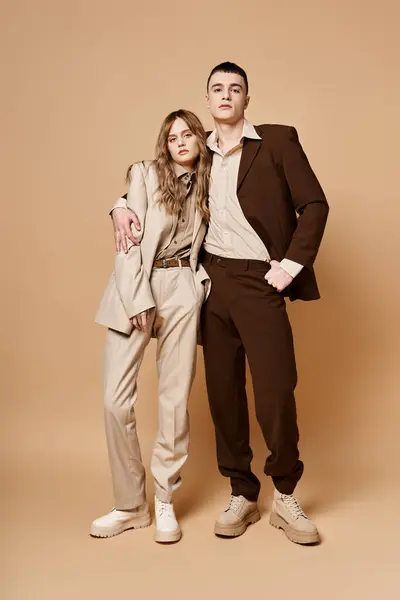 Liebevoll eleganter Freund und Freundin in schicken Anzügen mit Blick in die Kamera auf pastellfarbenem Hintergrund — Stockfoto