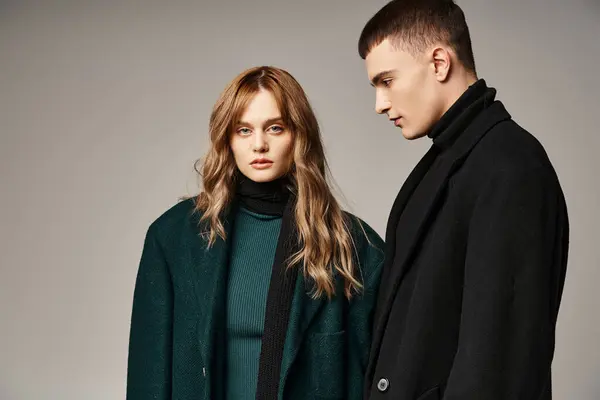 Fashionable man in coat posing lovingly next to his beautiful girlfriend who looking at camera — Stock Photo