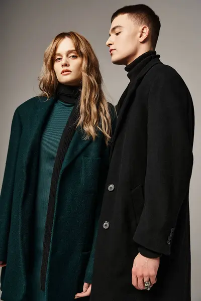 Gut aussehender Mann im Mantel posiert liebevoll neben seiner schönen Freundin, die in die Kamera schaut — Stockfoto