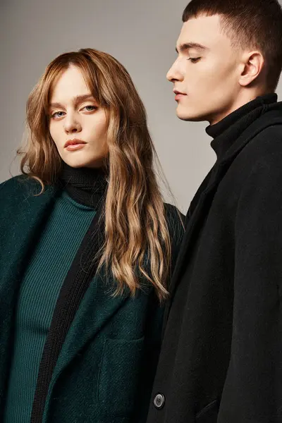 Attractive man in coat posing lovingly next to his beautiful girlfriend who looking at camera — Stock Photo