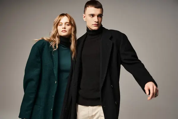 Handsome man in coat posing lovingly next to his beautiful girlfriend who looking at camera — Stock Photo