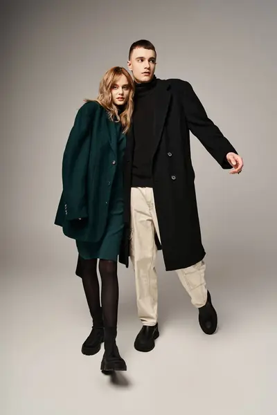 Bonito homem no casaco posando amorosamente ao lado de sua bela namorada que olhando para a câmera — Fotografia de Stock