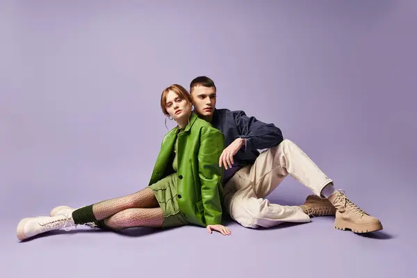 Красива стильна жінка в зеленому піджаку сидить на підлозі зі своїм хлопцем і дивиться на камеру — стокове фото
