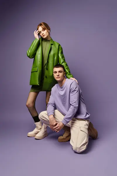 Модна пара в яскравому одязі позує разом на фіолетовому фоні і дивиться на камеру — стокове фото