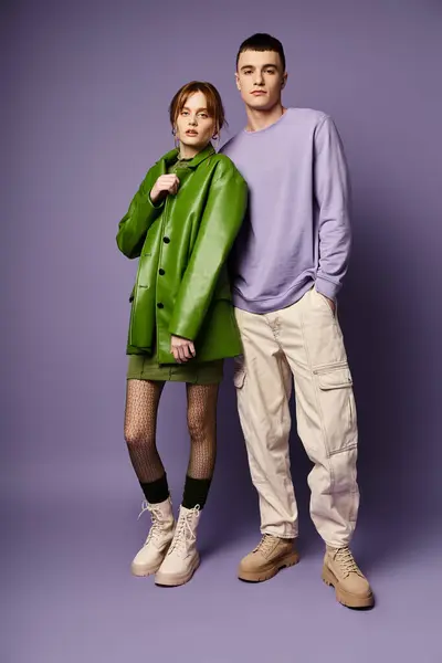 Modische Paar in lebendigen Kleidern posiert zusammen auf lila Hintergrund und blickt in die Kamera — Stockfoto