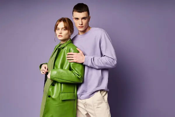 Сложная пара в яркой одежде позируют вместе на фиолетовом фоне и смотрят в камеру — стоковое фото