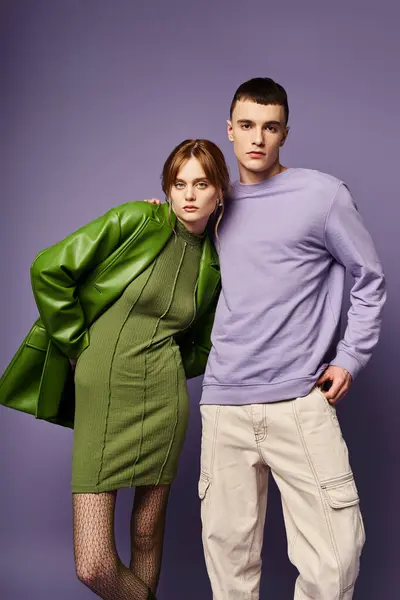 Ben vestito coppia in abiti vibranti in posa insieme su sfondo viola e guardando la fotocamera — Foto stock