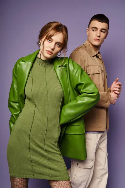 Bela mulher em traje verde olhando para a câmera ao lado de seu namorado bonito em pano de fundo roxo — Fotografia de Stock
