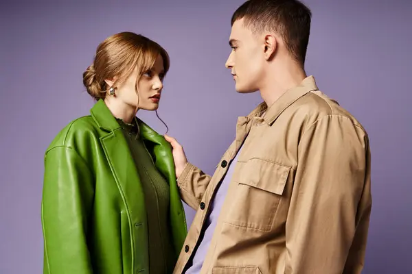 Seducente coppia amorevole in vivaci abiti colorati guardando l'un l'altro su sfondo viola — Foto stock