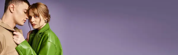 Femme élégante en veste verte regardant la caméra près de son petit ami aimant sur fond violet, bannière — Photo de stock