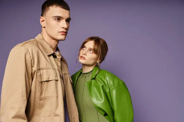 Attraente giovane donna in giacca verde guardando con amore il suo bel ragazzo su sfondo viola — Foto stock