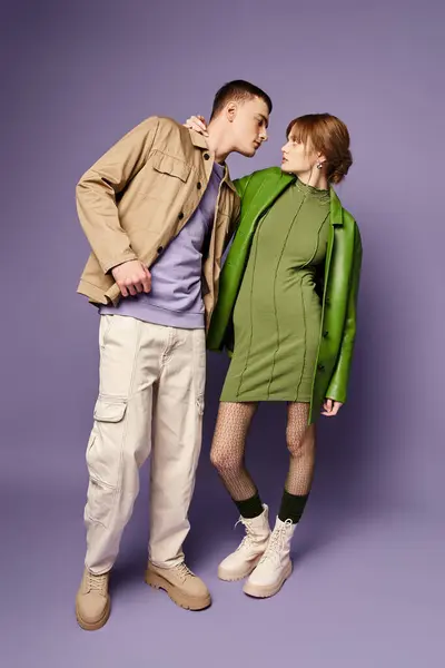 Seducente coppia amorevole in vivaci abiti colorati guardando l'un l'altro su sfondo viola — Foto stock