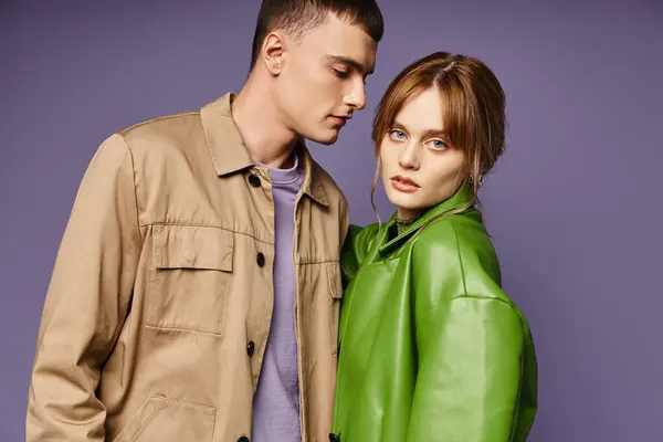 Beautiful woman in green jacket looking at camera near her loving boyfriend on purple backdrop — Stock Photo