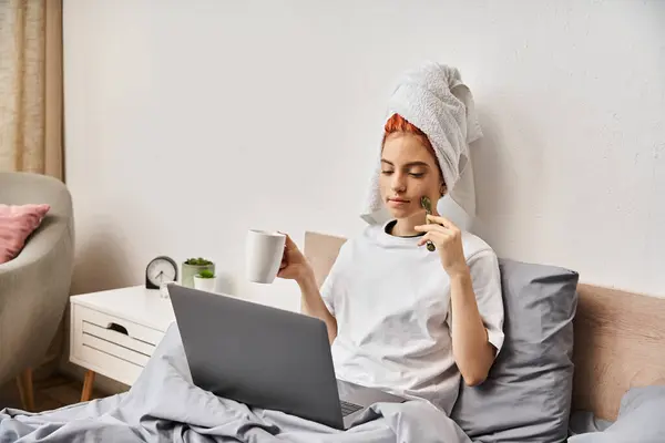 Bela pessoa queer com toalha de cabelo usando rosto rolo beber chá enquanto assiste filmes na tv — Fotografia de Stock