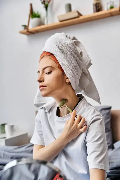 Bella persona queer in accogliente biancheria da casa utilizzando rullo viso davanti allo specchio come routine mattutina — Foto stock