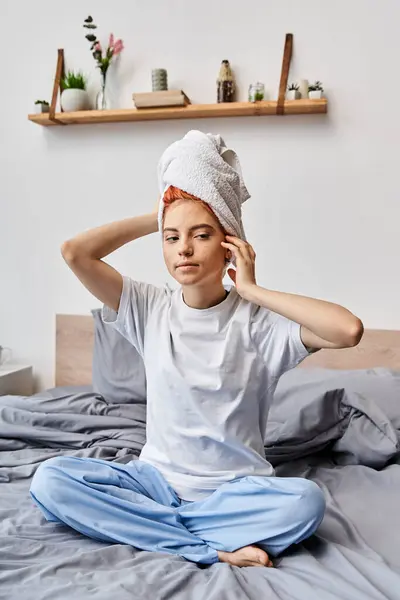 Pessoa extravagante atraente com toalha de cabelo branco sentado em sua cama em casa, rotina matinal — Fotografia de Stock