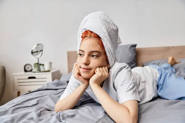Alegre bela queer pessoa em homewear com toalha de cabelo refrigeração em sua cama e olhando para longe — Fotografia de Stock