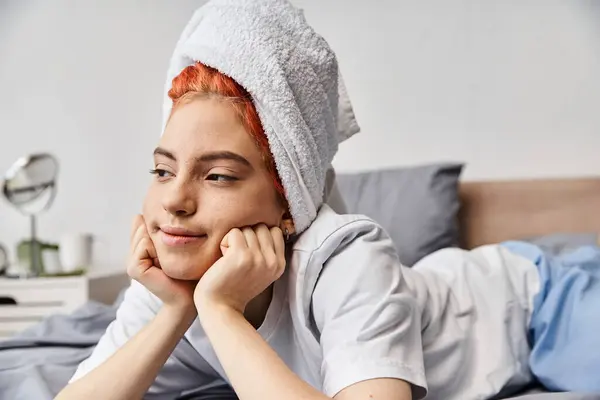 Alegre bela queer pessoa em homewear com toalha de cabelo refrigeração em sua cama e olhando para longe — Fotografia de Stock