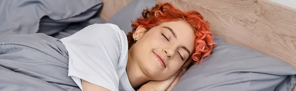 Belle personne queer aux cheveux roux en vêtements de maison sieste dans son lit à la maison, temps libre, bannière — Photo de stock