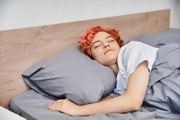 Belle personne queer aux cheveux roux dans des vêtements confortables sieste dans son lit à la maison, temps libre — Photo de stock