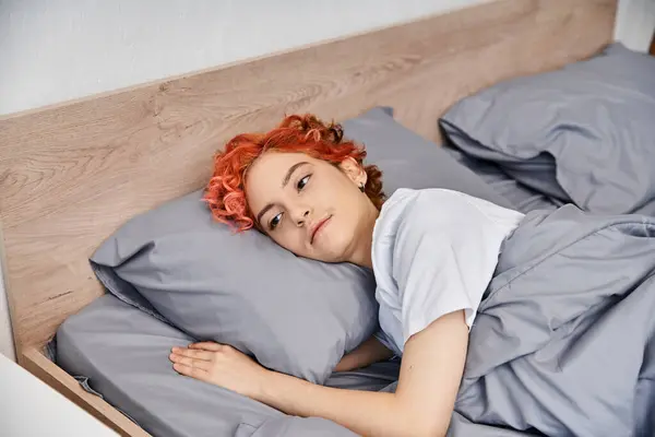 Stravagante giovane queer persona in abbigliamento casual svegliarsi e stretching nel suo letto, tempo libero — Foto stock