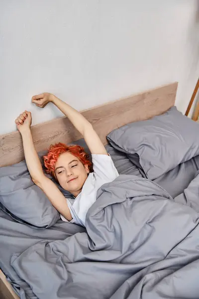 Stravagante bella persona queer in abbigliamento casual svegliarsi e stretching nel suo letto, tempo libero — Foto stock