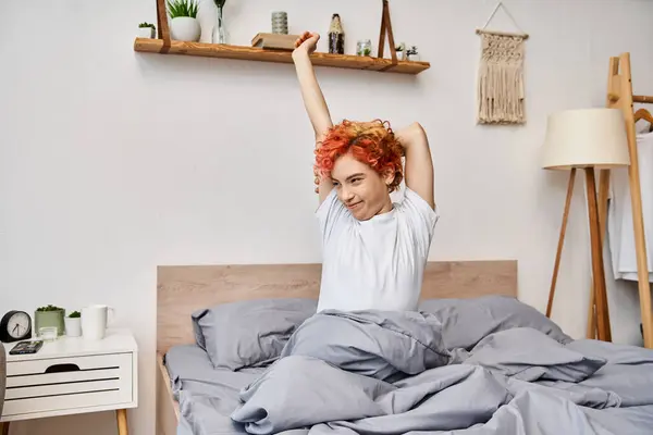 Stravagante bella persona queer in abbigliamento casual svegliarsi e stretching nel suo letto, tempo libero — Foto stock